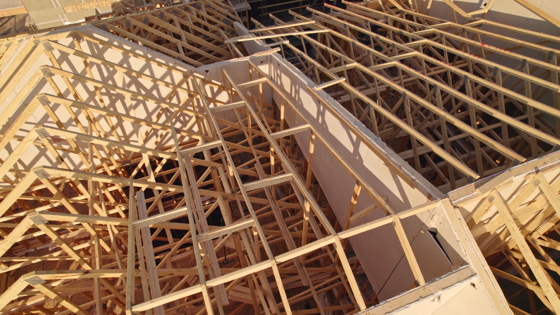 Modern North American home in construction. Aerial view of unfinished city house with wooden roof ribs frame structure. Roof beams under construction and inspection.