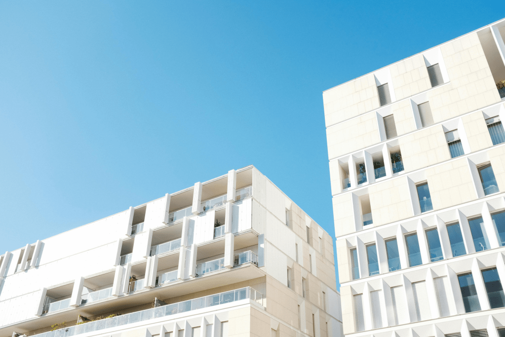 A low angle view of a white modern apartment building against a blue sky.